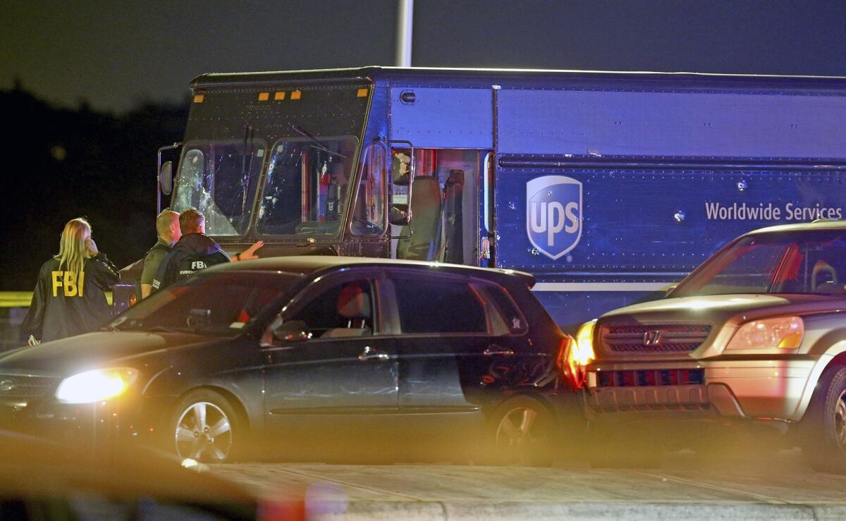 Law enforcement officials in Miramar, Fla., stand near the UPS truck that was carjacked along with its driver. The two carjackers were killed.