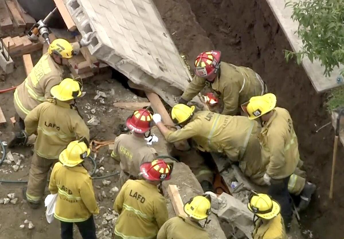 Los Angeles Fire Department crews work to rescue a person trapped under a wall that fell at a construction site in Pacoima.