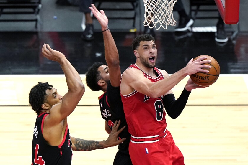 Chicago Bulls guard Zach LaVine, right, drives to the basket against Toronto Raptors center Khem Birch, left, and guard Jalen Harris during the first half of an NBA basketball game in Chicago, Thursday, May 13, 2021. (AP Photo/Nam Y. Huh)