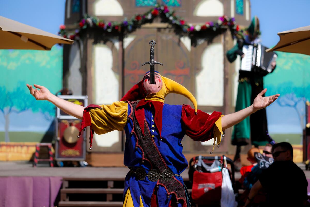 A performer in colorful jester gear swallows a sword.