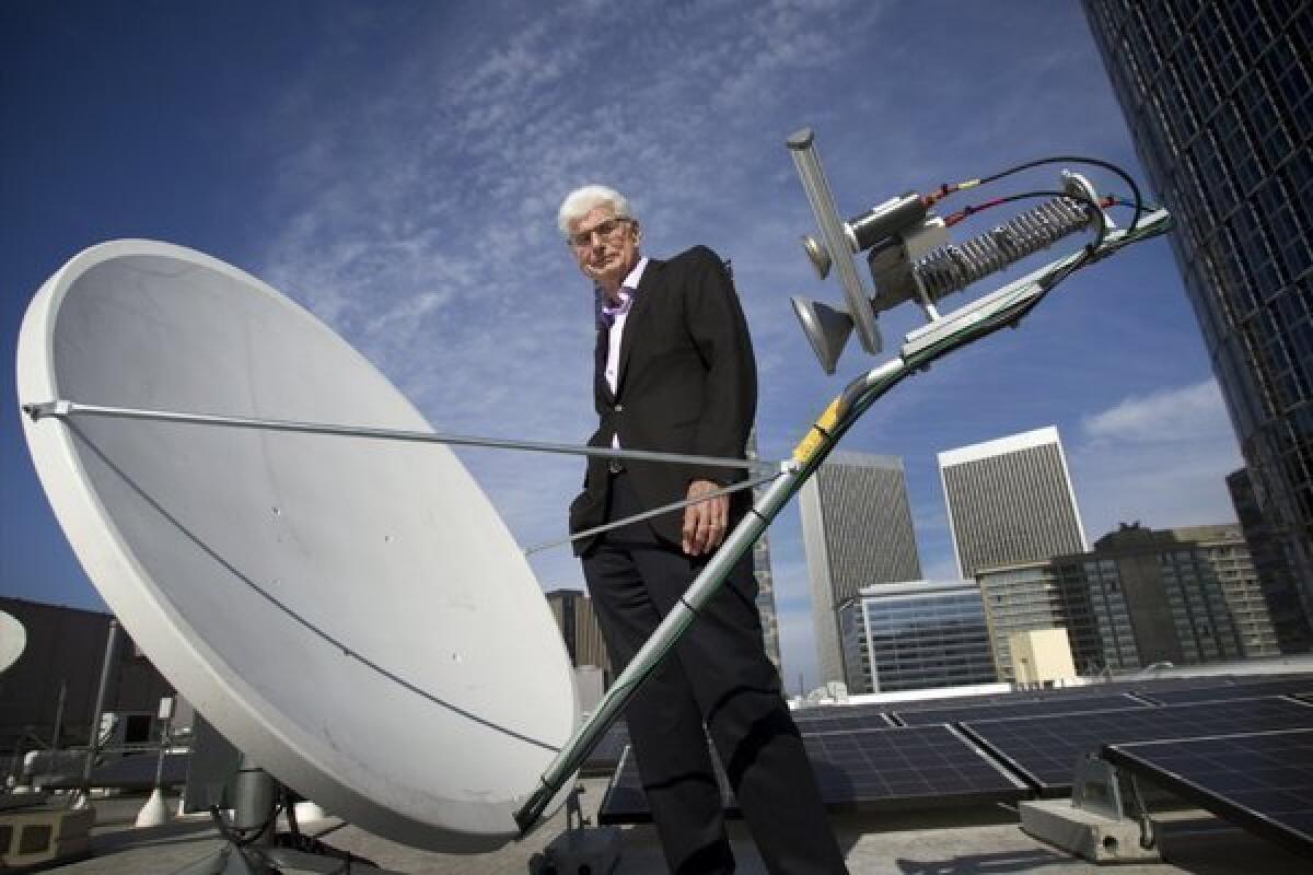 Randy Blotky, chief executive of the Digital Cinema Distribution Coalition, stands by a satellite dish on the roof at the AMC Century City 15 theater. The satellite network significantly reduces the price of showing movies in theaters.