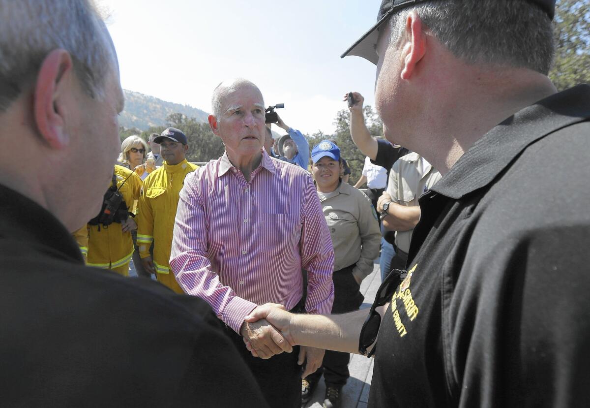 Gov. Jerry Brown shakes hands with first responders at Cowboy Camp Trailhead near Clear Lake, where the Rocky fire has destroyed homes.