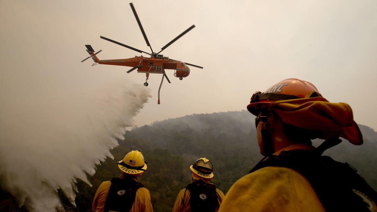 Firefighters watch as a helicopter drops water on the Alamo fire near Santa Maria on Saturday.