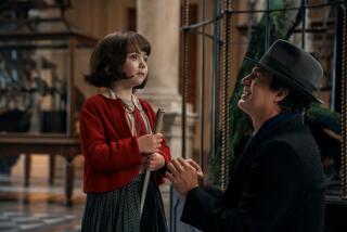 A man in a dark coat and hat crouches to speak with a young girl in a red sweater holding a cane
