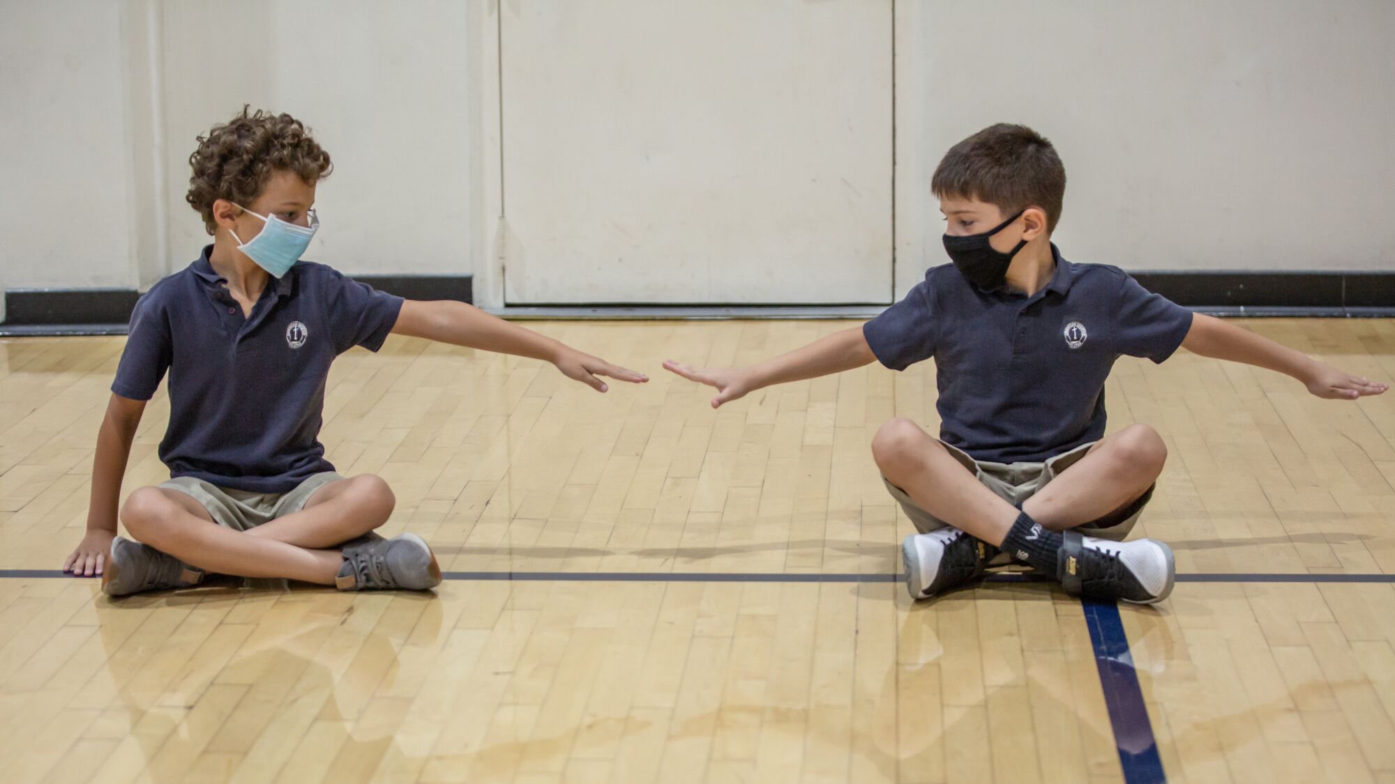 Second graders at Christian Unified, Nick and Liam, measure their distance during gym class. 