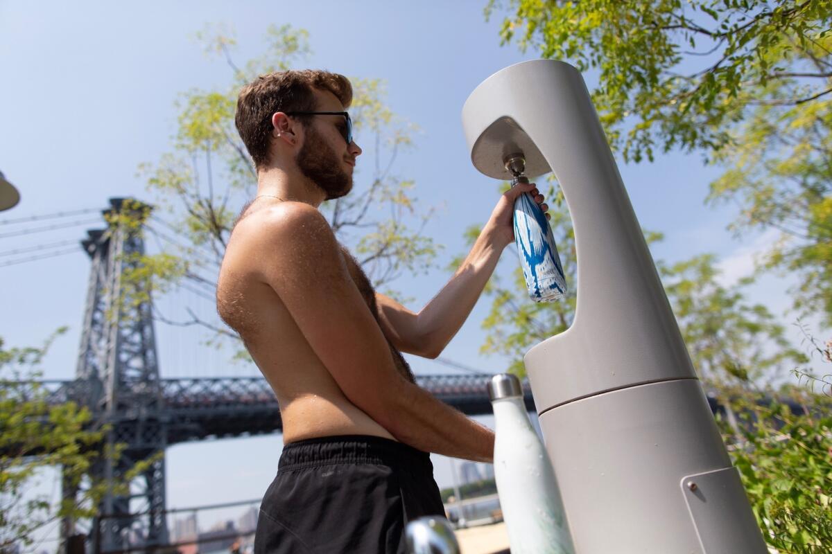 Un hombre rellena su bote con agua en un parque cuando las temperaturas rondan los 34-37 centígrados (arriba de 90 Fahrenheit) en Williamsburg, Brooklyn, el sábado 20 de julio de 2019. (AP Foto/Eduardo Munoz Alvarez)