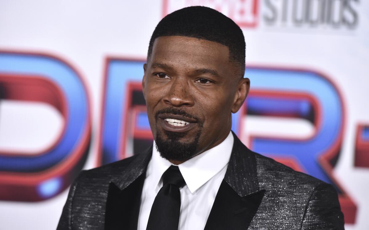 Jamie Foxx in a metallic suit, a white shirt and black tie