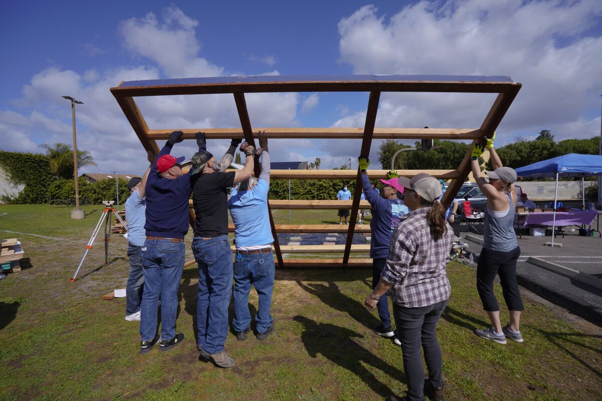 People raise a wood frame for a small cabin