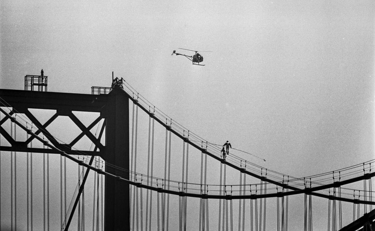 April 2, 1976: A helicopter observes tightrope walker Steve McPeak's journey over the Vincent Thomas Bridge. His assistant, Celeste Farr, accompanies him.