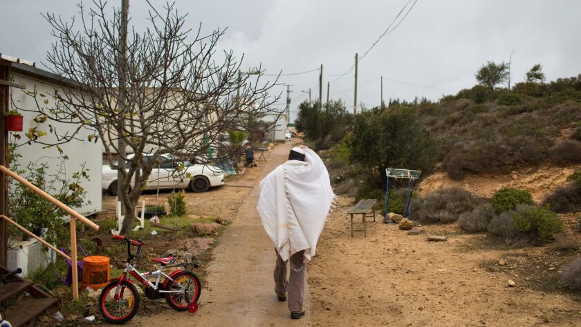 A Jewish settler walks home after morning prayers in Amona, an unauthorized outpost in the West Bank, on Dec. 18, 2016.
