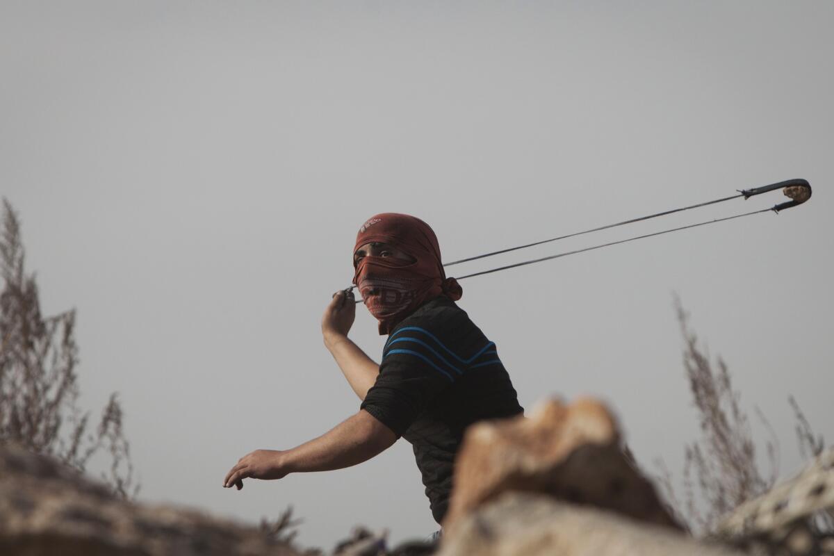 A Palestinian uses a sling shot during clashes with Israeli forces Friday at the Kalandia checkpoint near Jerusalem.