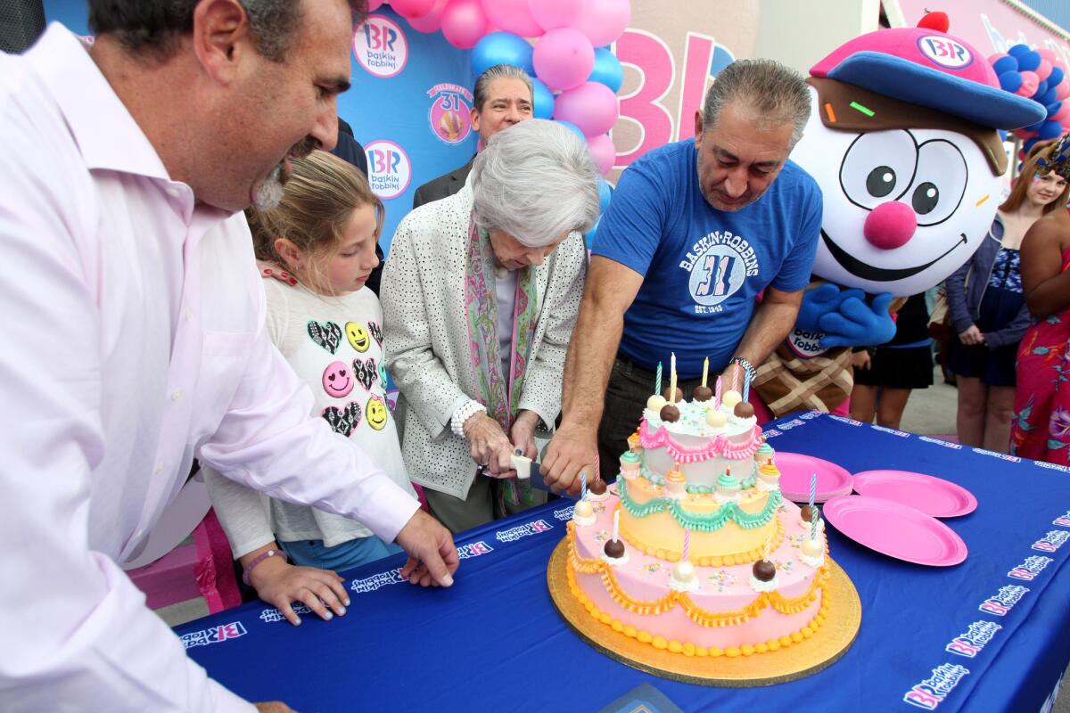 With director of operations Andy Hasson looking on at left,Shirley Baskin, wife of Baskin-Robbins co-founder Burt Baskin, and franchise owner Baruzh Tirityan cut the cake during Baskin-Robbins 70th anniversary celebration at the franchise on Victory Boulevard in Burbank on Tuesday, Dec. 8, 2015.