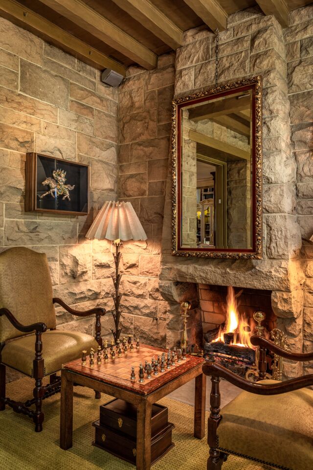 The den has a fireplace built into the stone walls.