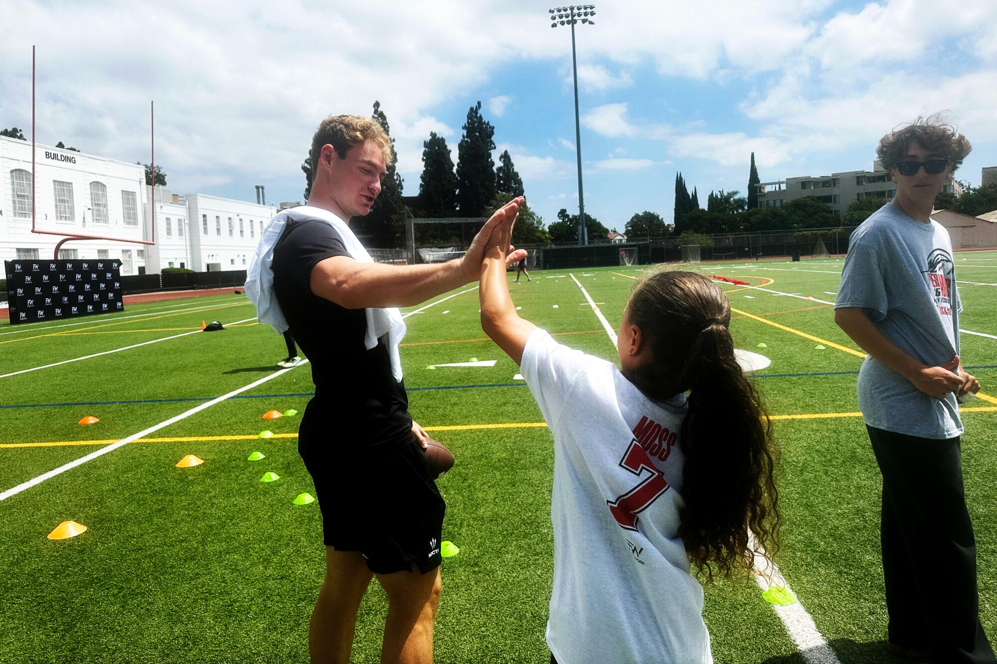 Former USC quarterback Miller Moss high fives a participant at his football camp at Beverly Hills High School.