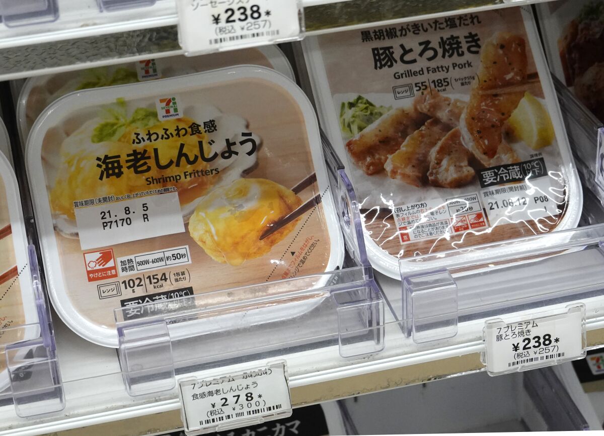Food packages are labeled "Shrimp Fritters" and "Grilled Fatty Pork" at a 7-Eleven in Tokyo.