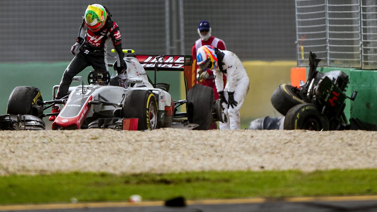 Formula One drivers Esteban Gutierrez, left, and Fernando Alonso exit their cars after colliding and crashing during the Australian Grand Prix at the Albert Park in Melbourne.