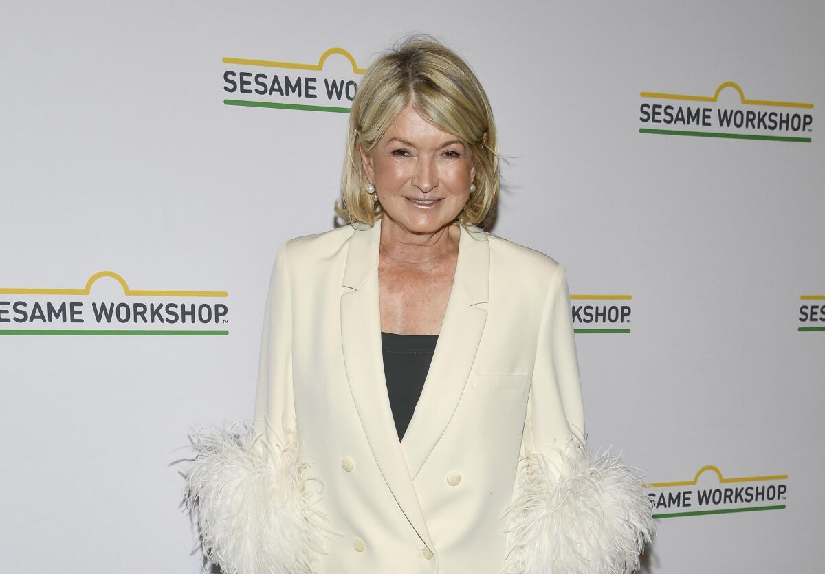 Martha Stewart wears an off-white blazer with dramatic feather-cuffed sleeves over a black shirt