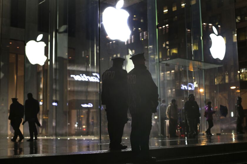 Police officers stand outside an Apple Store on Fifth Avenue in New York while monitoring a rally by supporters of Apple's stance against the FBI on Tuesday.