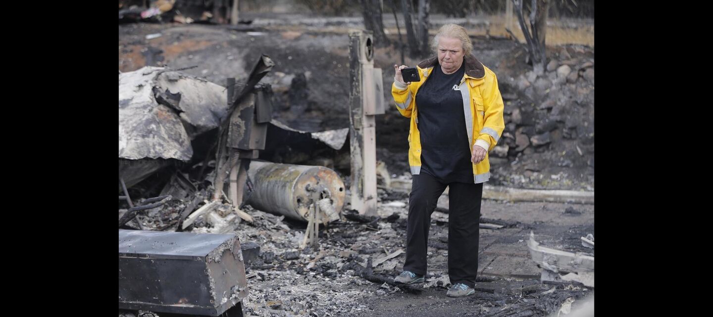 Claudette Sanders takes video of the charred remains of her mobile home in the Alpine Oaks Estates burned in the West Fire.