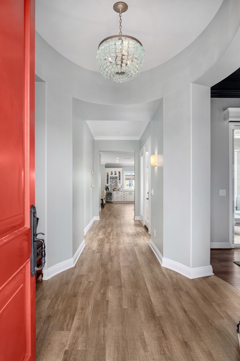 Luxury vinyl plank flooring is seen in a long vertical view from the front door, stretching to the kitchen.