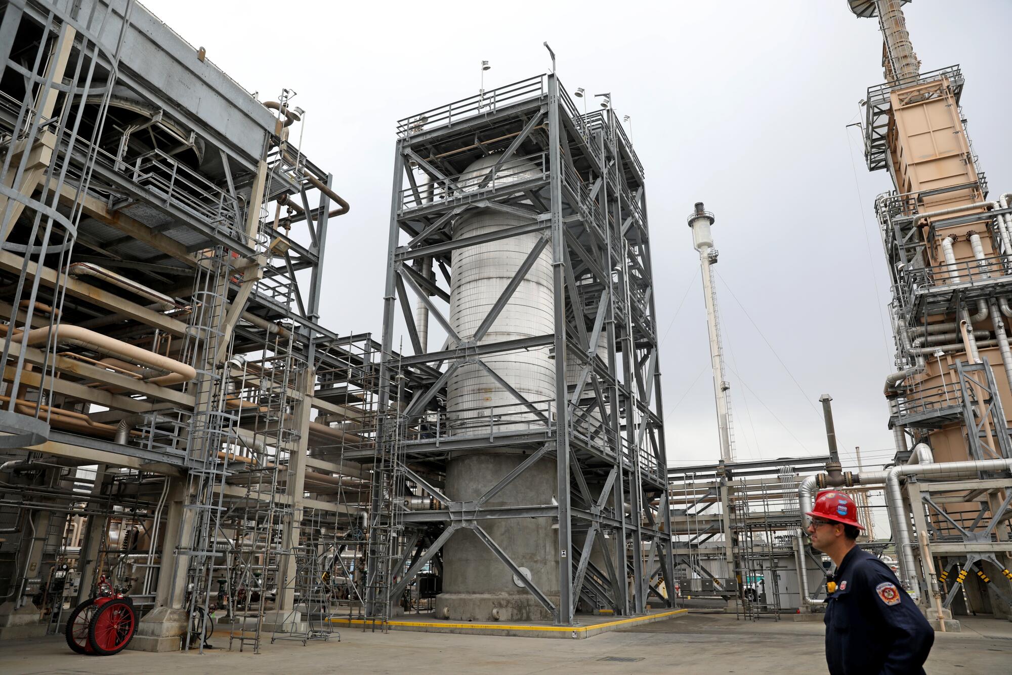 Tyler Bagley, wearing a hardhat, stands next to a massive machinery. 