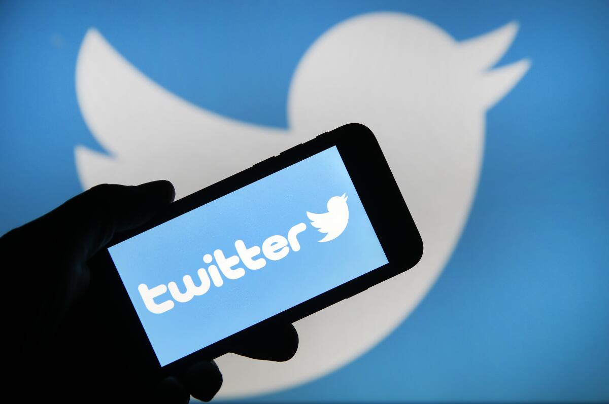 Photo illustration of the Twitter logo displayed on the screen of a smartphone.