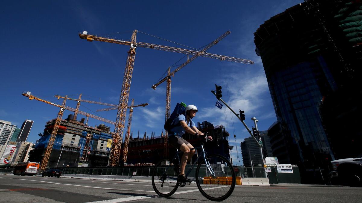 Construction cranes loom over a development site along Figueroa Street near the L.A. Live entertainment and hotel complex in downtown Los Angeles.