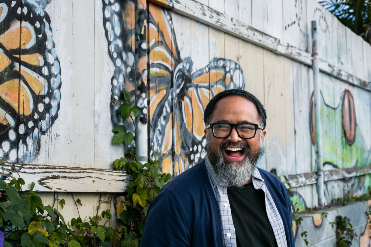 Jason Magabo Perez, the city of San Diego's new poet laureate, poses in front of a mural on Thursday.