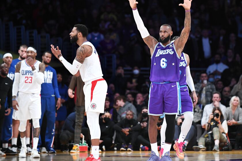 LOS ANGELES-CA-FEBRUARY 25, 2022: Los Angeles Lakers' LeBron James, right, and Los Angeles Clippers' Marcus Morris Sr., left, await a review of a call in the final seconds of the game at Crypto.com Arena in downtown Los Angeles on Friday, February 25, 2022. (Christina House / Los Angeles Times)