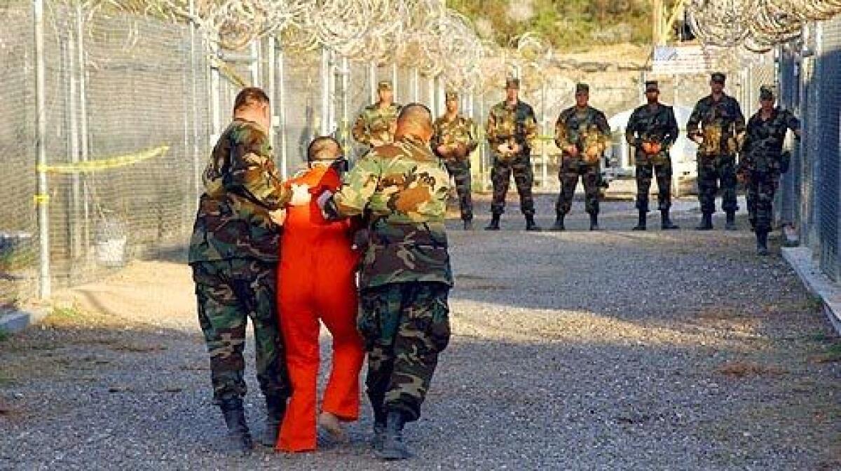 ON THE INSIDE: Army military police escort a detainee to his cell in Camp X-Ray at Guantanamo Bay in January 2002 shortly after the prison opened.