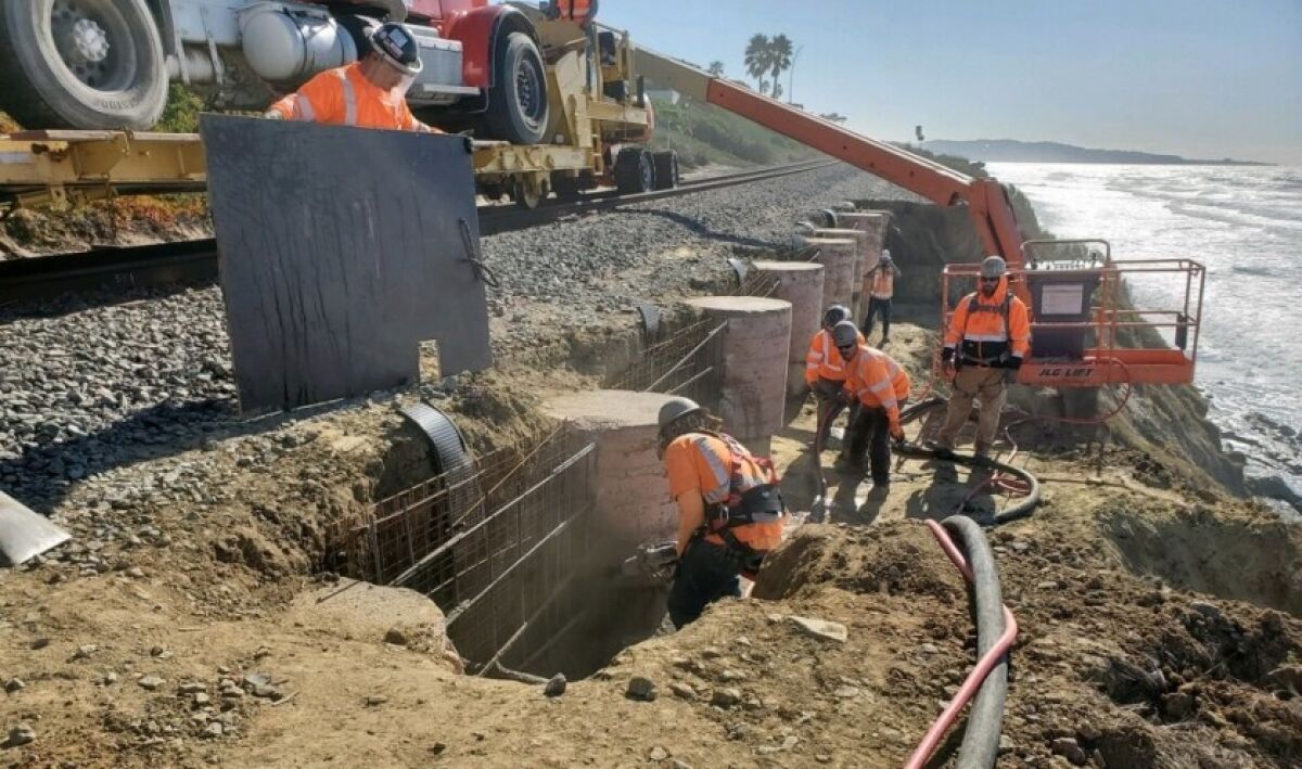 Workers build a wall along the tracks on the bluff in Del Mar over the weekend.