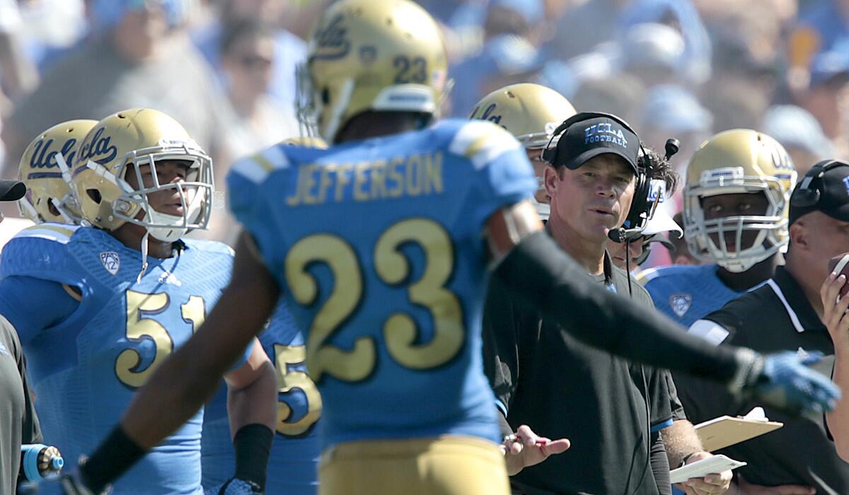 UCLA Coach Jim Mora encourages defensive back Anthony Jefferson to keep his cool after a teammate was called for a penalty in the first half.