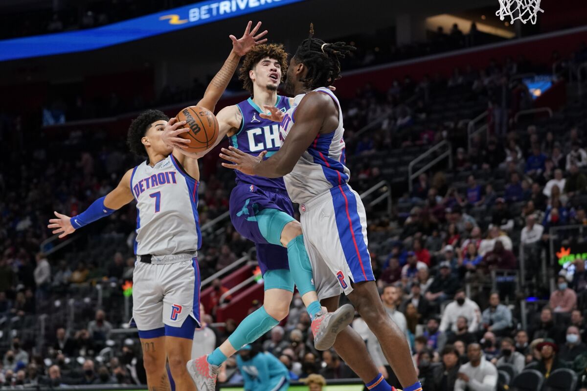 Charlotte Hornets guard LaMelo Ball (2) drives on Detroit Pistons center Isaiah Stewart (28) and Killian Hayes (7) in the first half of an NBA basketball game in Detroit, Friday, Feb. 11, 2022. (AP Photo/Paul Sancya)