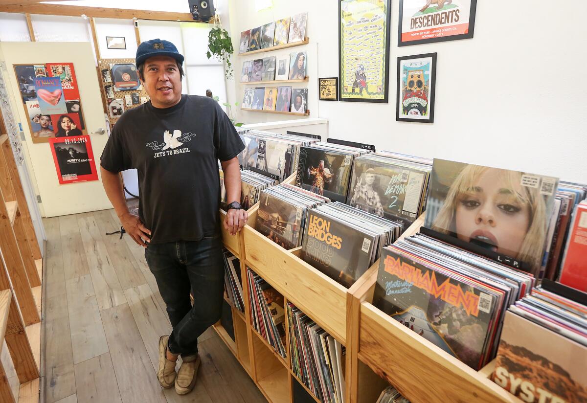 Owen Ela stands next to album bins at Resident Vinyl inside Contra Coffee in Old Towne Orange.