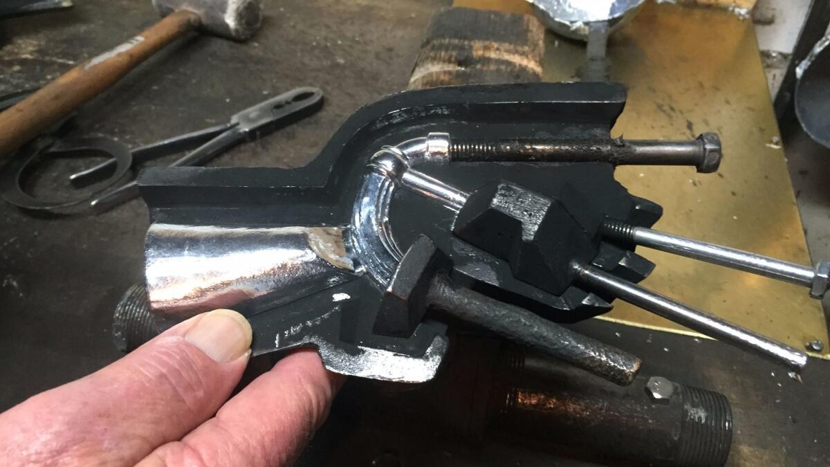 John Billings examines the tone arm of a Grammy. The arm holds up the bell.