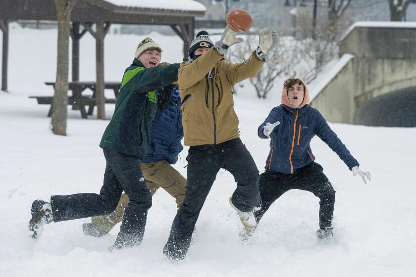 Liam McGreevy, left, Lucas Acerenza and Porter Jones play football in the snow at Baker Park Friday, Jan. 19, 2024 in Frederick, Md. The three Frederick High School students had the day off as Frederick County schools were closed. (Ric Dugan/The Frederick News-Post via AP)