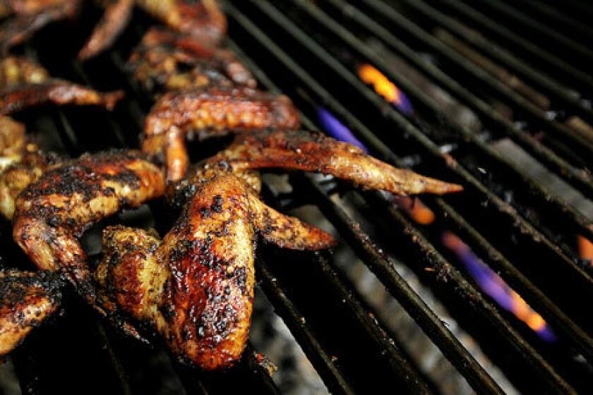 Reggae wings cook on the grill at Front Page Jamaican Grille in Inglewood.