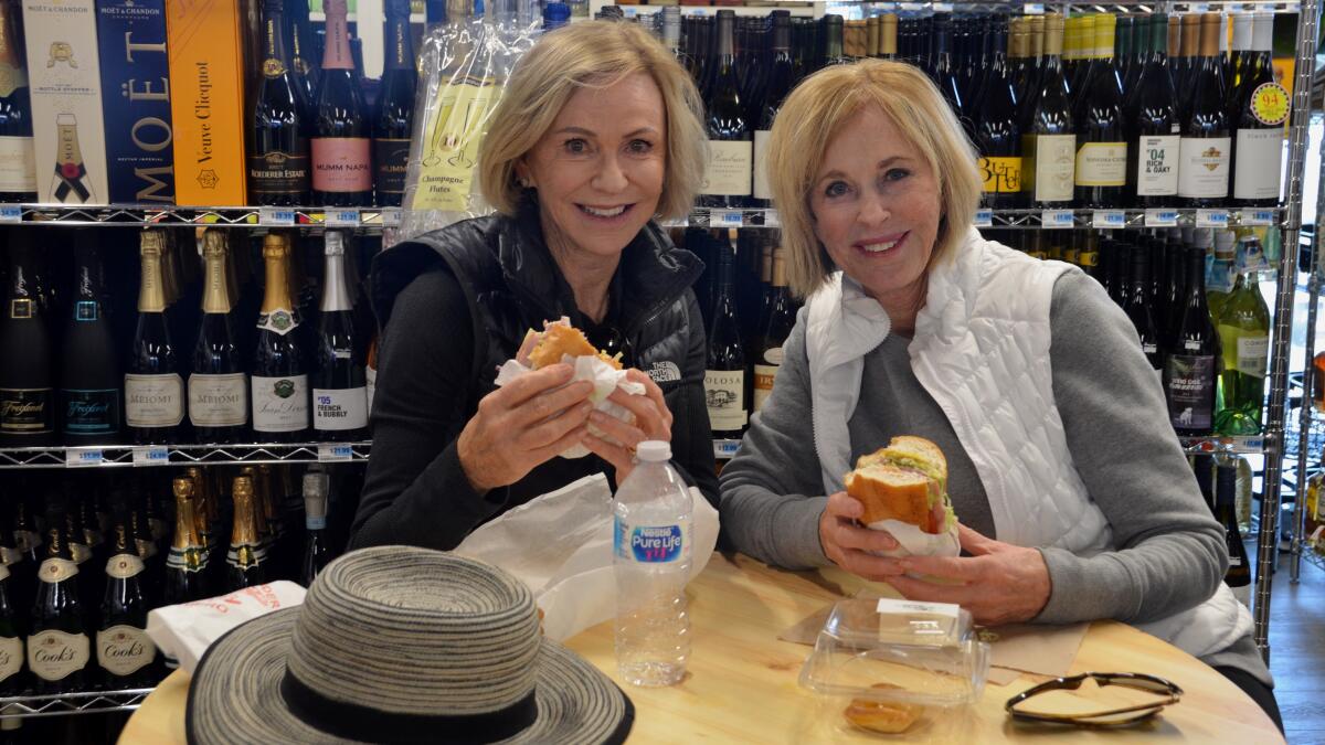 Dee Higby, left, and Janet Sanders dig into fresh-made Godfather Italian sandwiches at Irvine Ranch Market in Newport Beach on Wednesday.