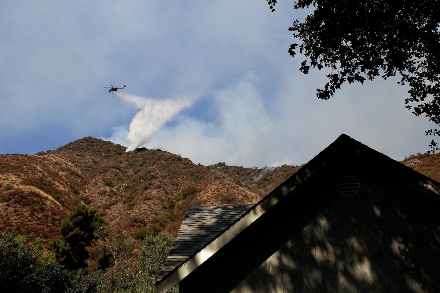 An Orange County Fire Authority helicopter makes a water drop on a brush fire near homes on Silverado Canyon Road.