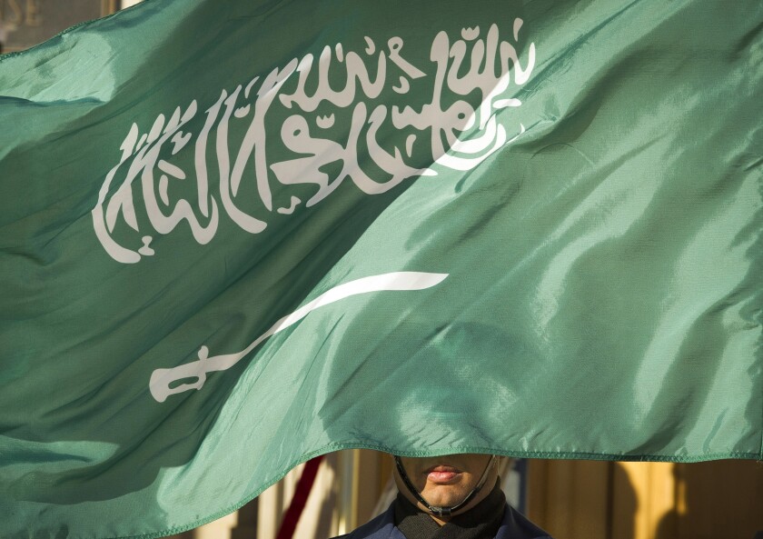 FILE - In this March 22, 2018, file photo, an honor guard member is covered by the flag of Saudi Arabia in Washington. Saudi Arabia executed a young man Tuesday, June 15, 2021, who was convicted on charges stemming from his participation in an anti-government rebellion by minority Shiites. It was unclear whether Mustafa bin Hashim bin Isa al-Darwish, 26, was executed for crimes committed as a minor, according to Amnesty International, who said his trial, however, was “deeply flawed.” (AP Photo/Cliff Owen, File)