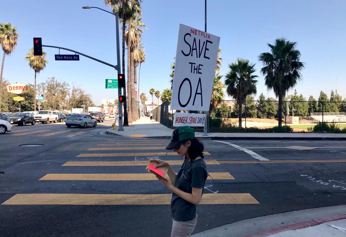 Emperial Young with her "Save the OA" sign, standing on the corner of Sunset Blvd. and Van Ness in Hollywood outside Netflix.