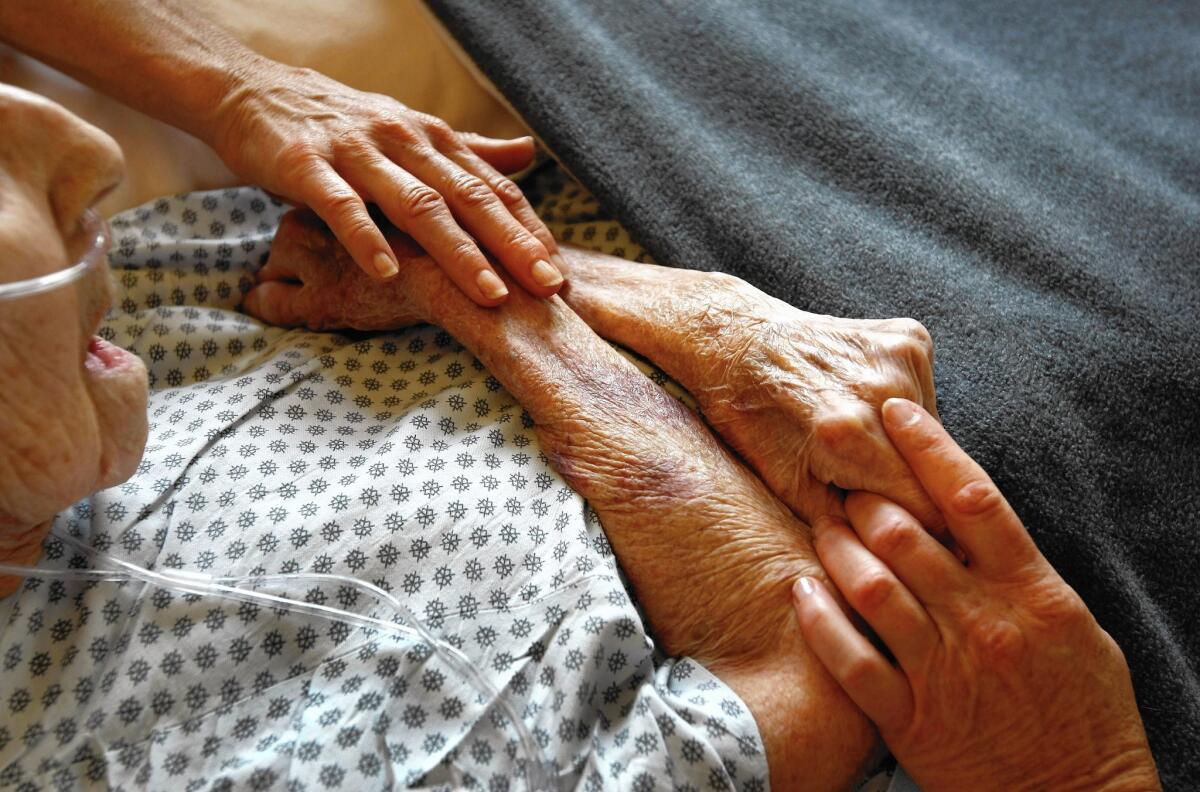 Hospice volunteers in Lakewood, Colo., comfort a terminally ill patient in September.