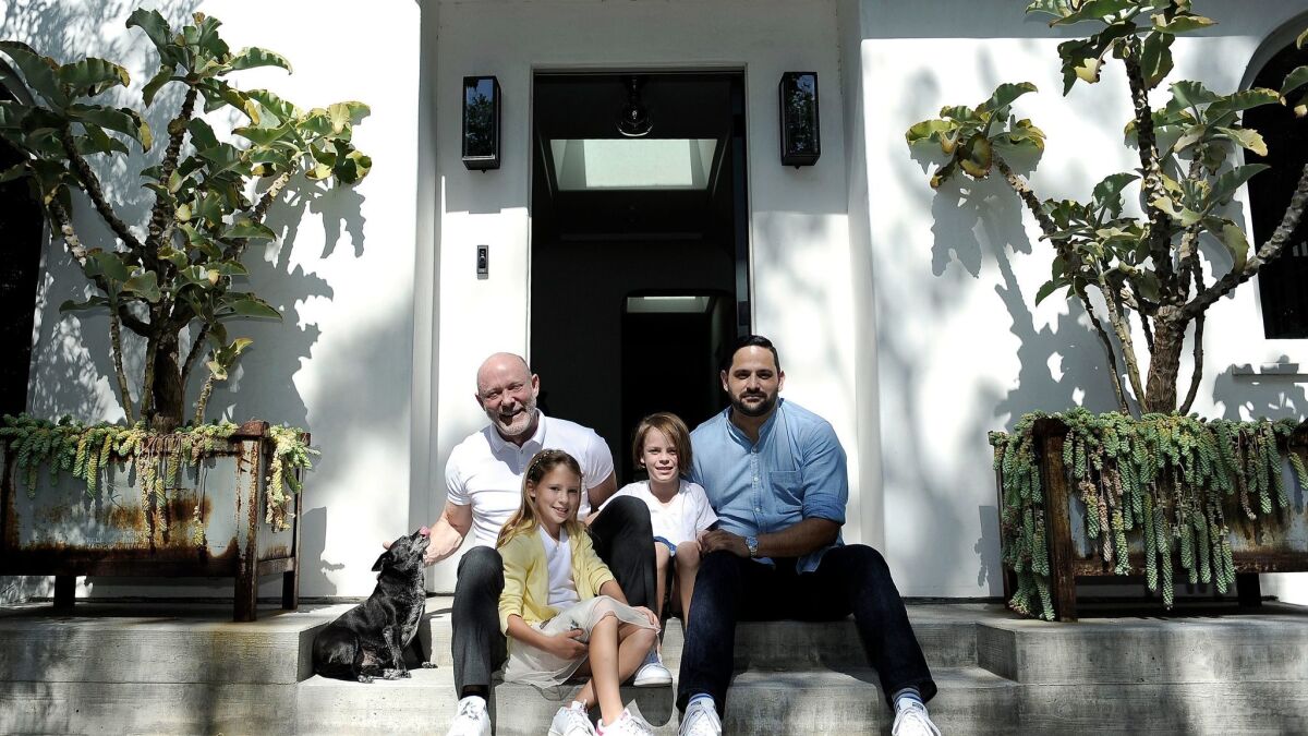 David Collins, left, his daughters Olive and Ella, and David's partner, Joseph Rivas, sit between potted succulents on either side of the front door, which welcome guests in dramatic fashion.