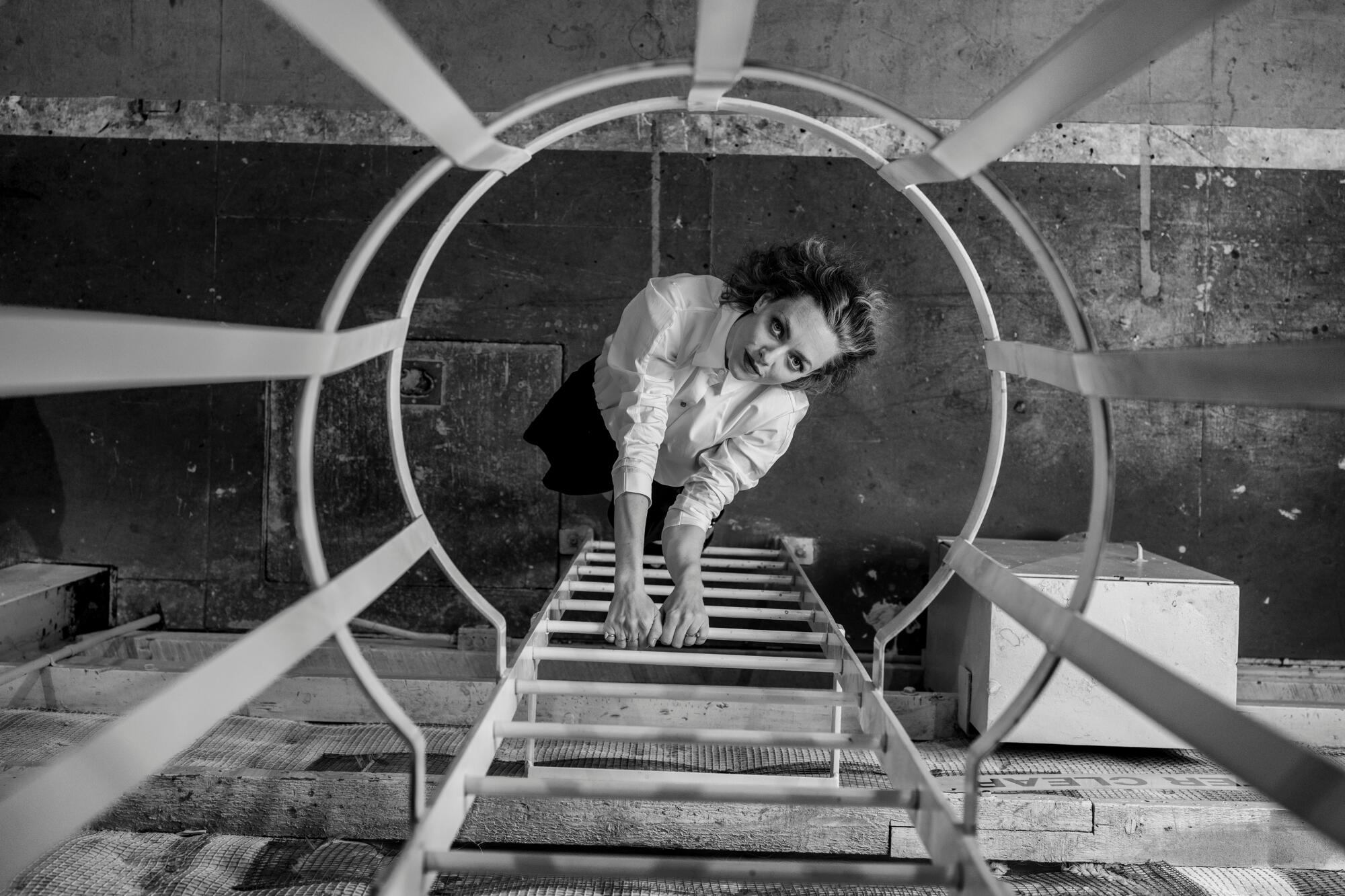 A woman is seen climbing a ladder from a top-down perspecitive 