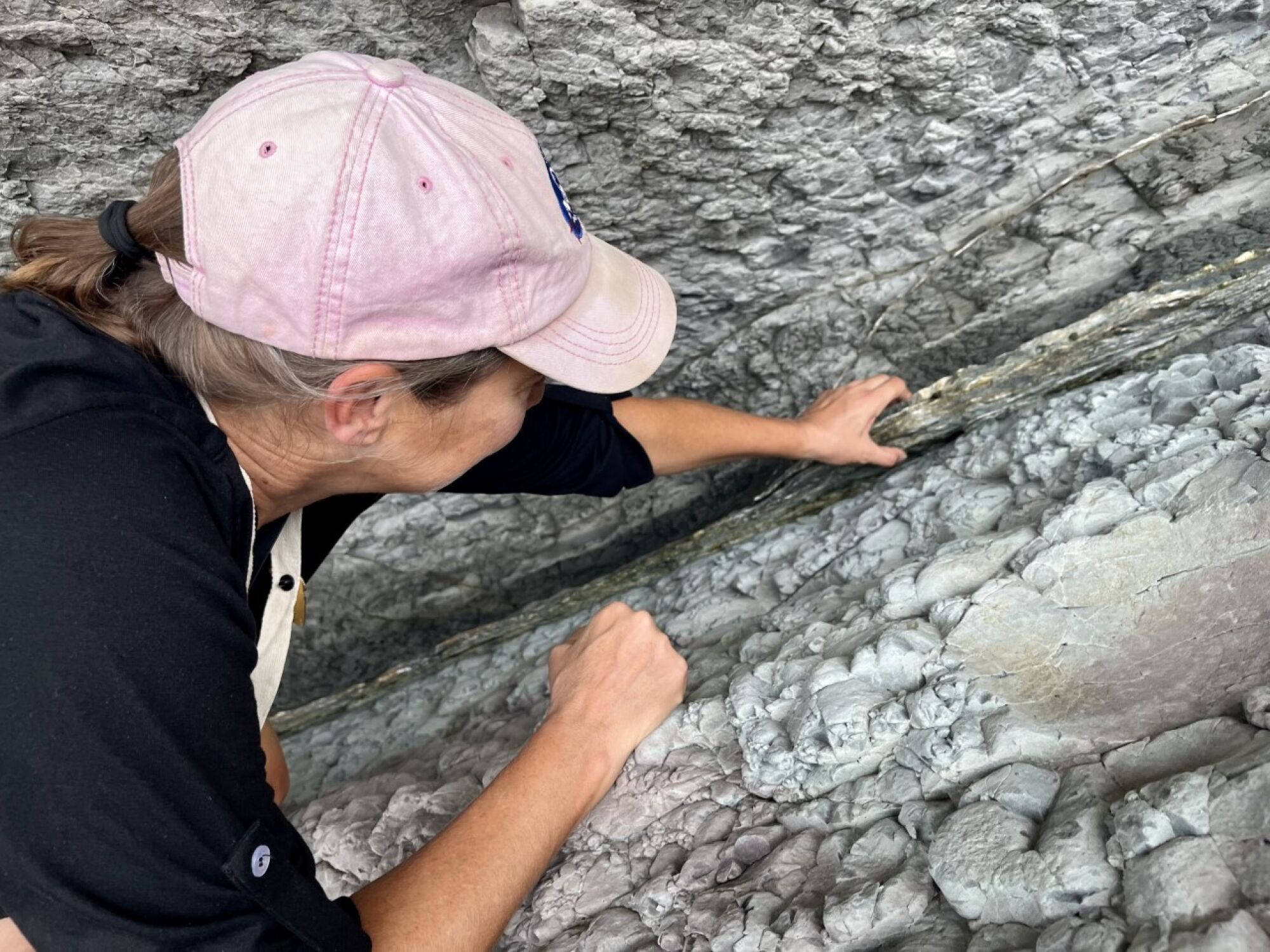 La Brea Tar Pits curator Regan Dunn places her hand on the K/Pg boundary of Zumaia’s flysch in Zumaia, Spain.
