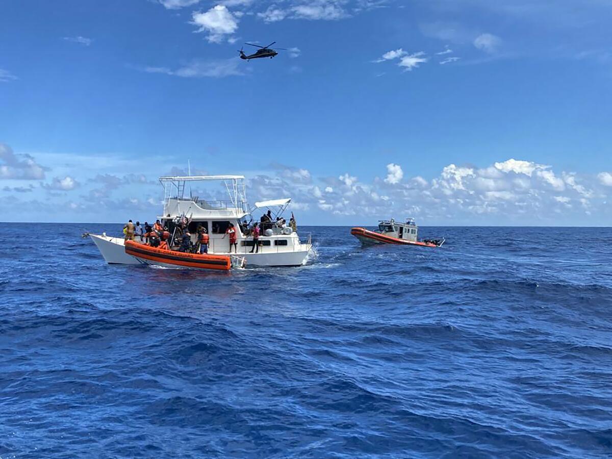 This image provided by the U.S. Coast Guard shows Coast Guard law enforcement crews aiding people from an unsafe and overloaded 40-foot cabin cruiser about 20 miles off Boca Raton, Fla., Oct. 12, 2022. The people were transferred to Bahamian authorities, Oct 16, 2022. (U.S. Coast Guard via AP)