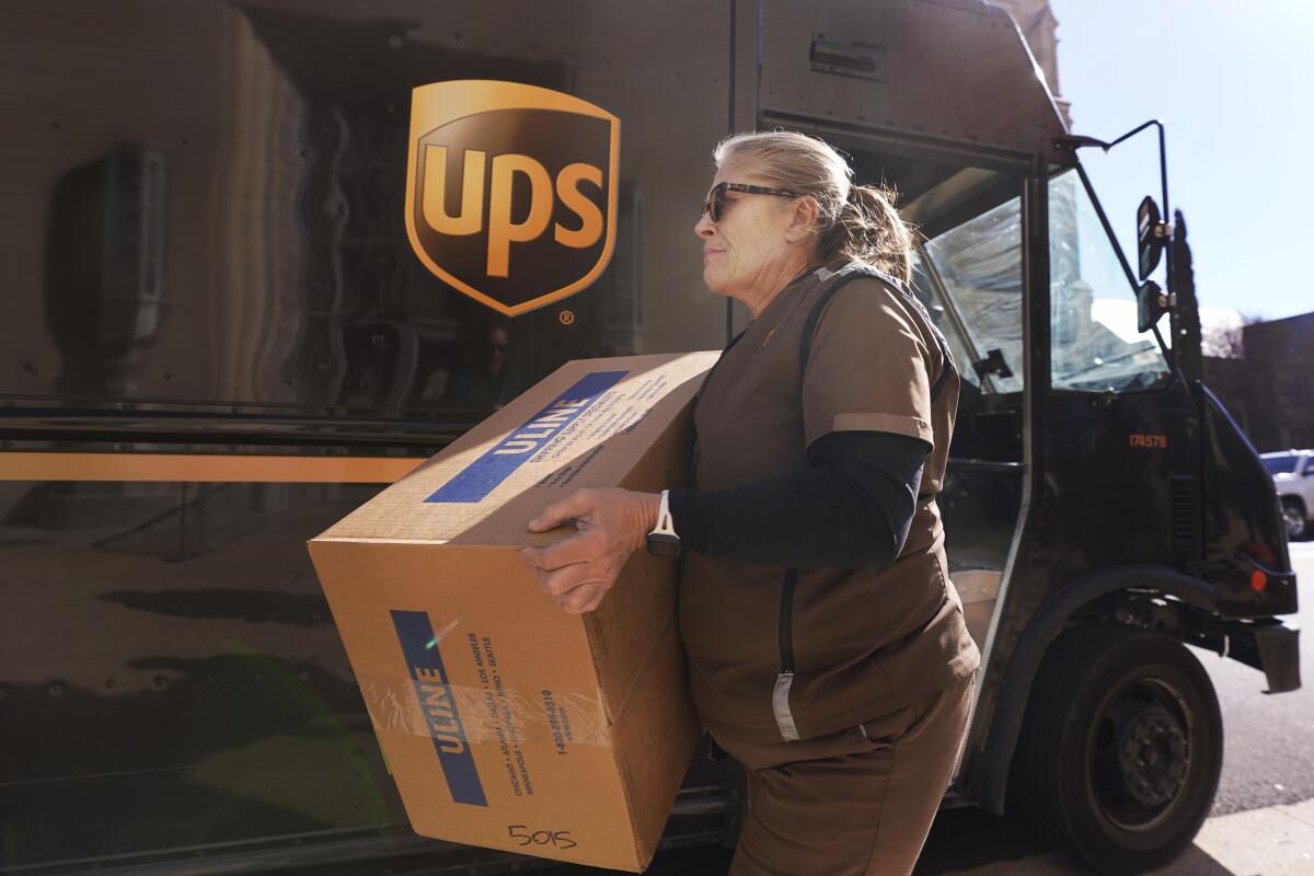 A UPS delivery person carries a package from a truck. 