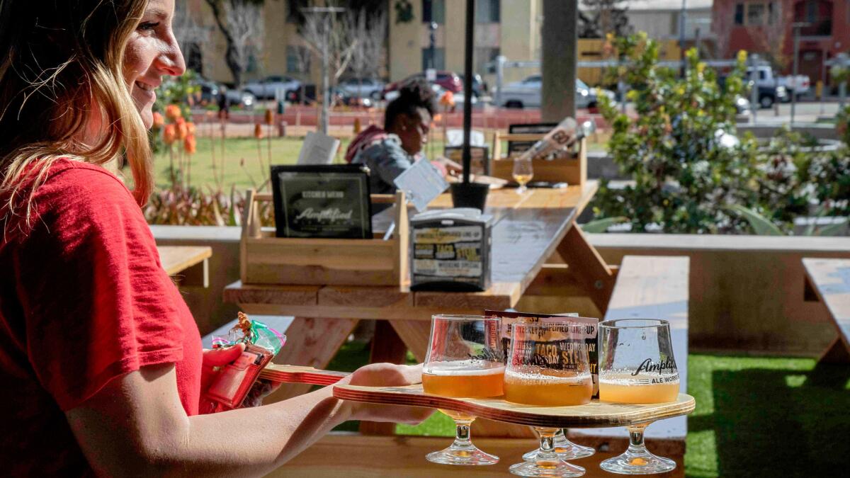 Customer carrying a flight of beer samplers at Amplified Ale Works in San Diego.