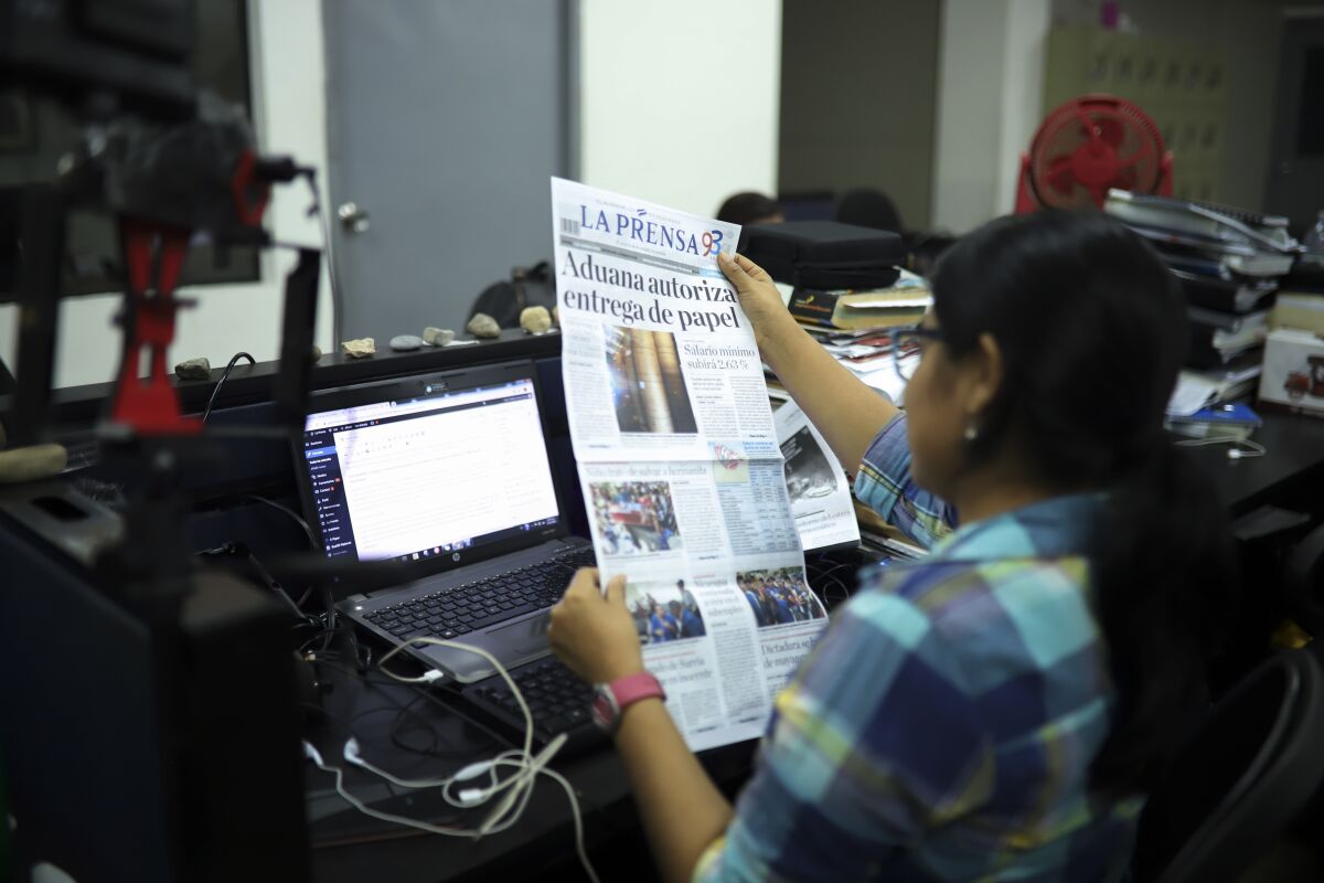 FILE - A journalist holds up a copy of La Prensa independent newspaper with a headline that reads in Spanish; "Customs authorizes release of printing paper," in Managua, Nicaragua, Friday, Feb. 7, 2020. La Prensa, the country´s oldest and most influential newspaper, whose building has been occupied by the polices for almost a year, informed on Thursday, July 21, 2022, that its whole news staff has been forced to leave the country due to government persecution. (AP Photo/Alfredo Zuniga, FIle)