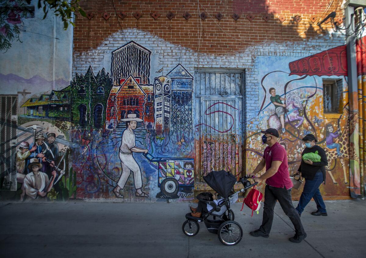 Joe Hernandez pushes the stroller with his 2-year-old daughter, Brandy, inside as he walks with Helen Silbas in Santa Ana.